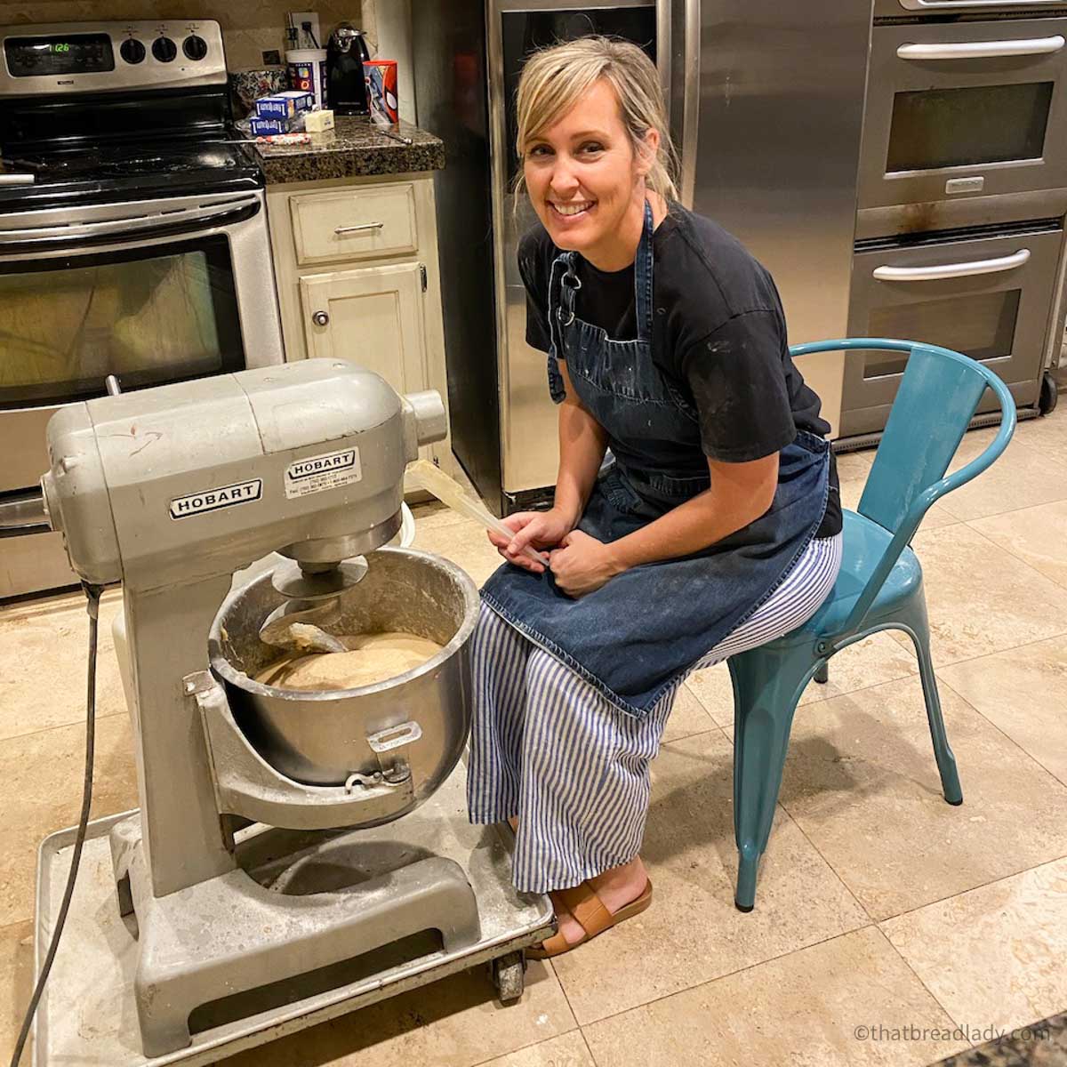 Heather sitting at her floor mixer in her home bakery.
