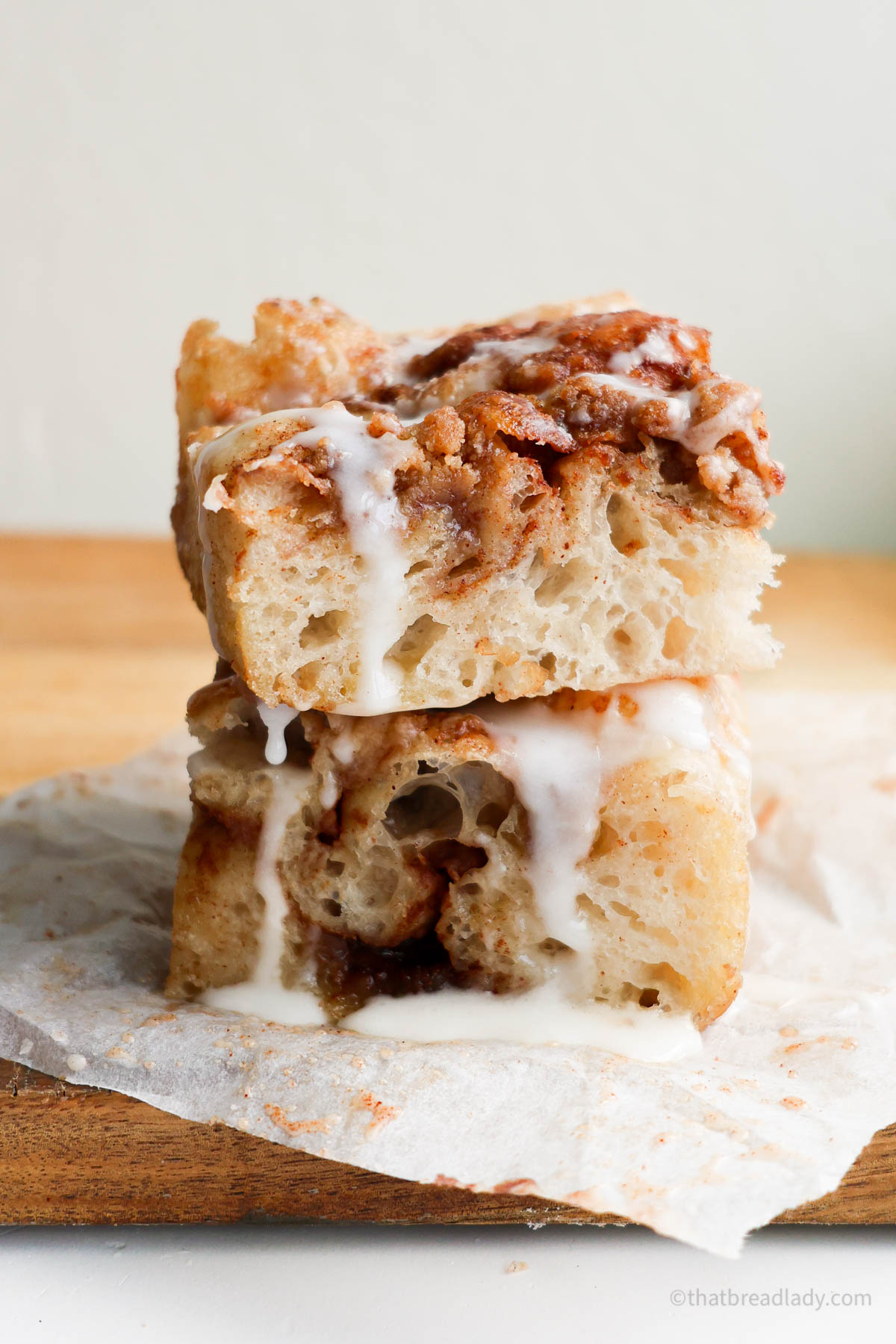 Two slices of cinnamon roll focaccia stacked on top of each other with icing dripping down the side.