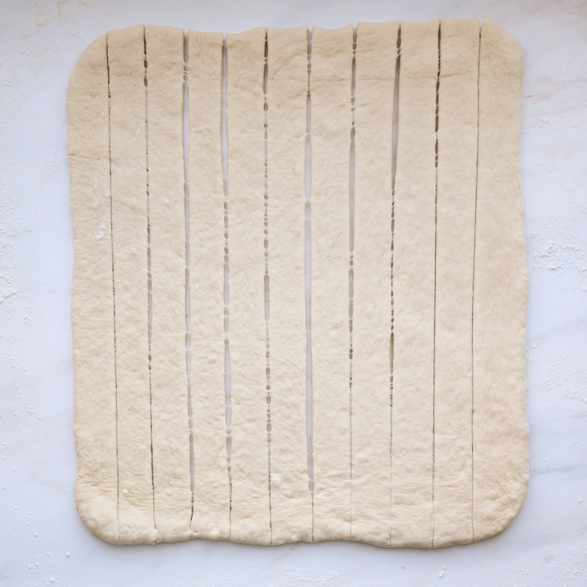 A 12 by 18-inch rectangle of bread dough, cut into 12, 1-inch strips.