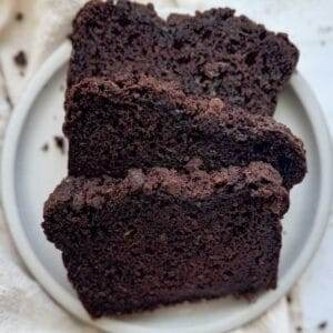 Three slices of double chocolate zucchini bread on a white plate.