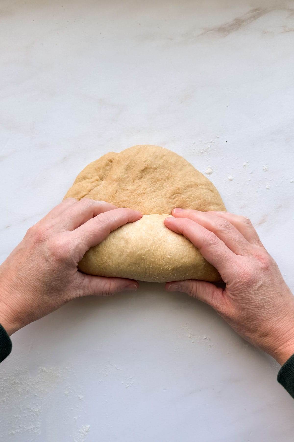 Two hands rolling up the loaf of honey whole wheat bread.