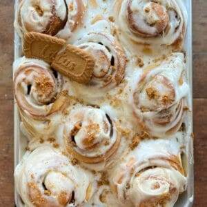 A pan of biscoff cinnamon rolls with a cookie on top.