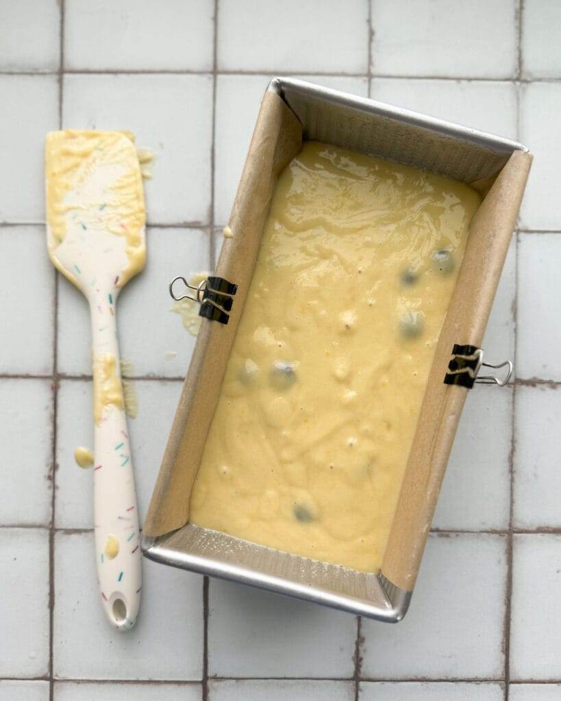 Lemon Blueberry batter in a loaf pan lined with parchment paper