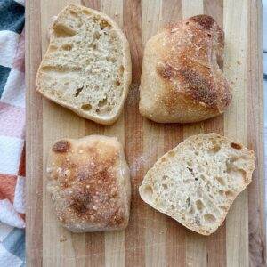 4 ciabatta rolls on a wood cutting board.