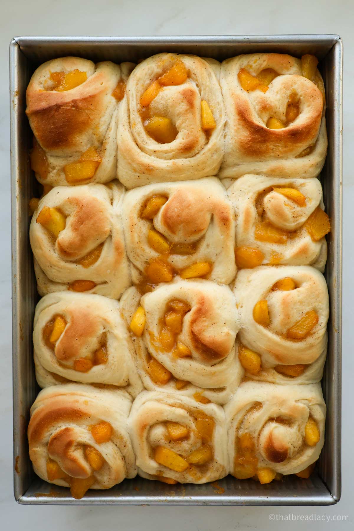 A 9x13 pan of baked peach cinnamon rolls.