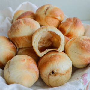 A basket full of resurrection rolls with one open and hollow inside.