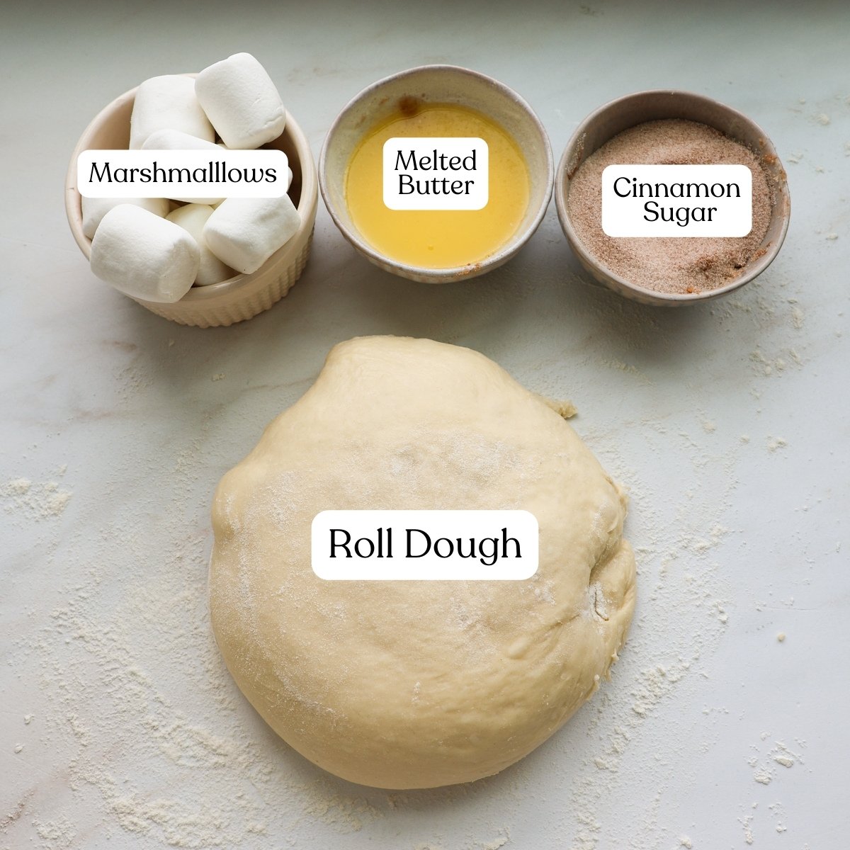 A bowl of marshmallows, melted butter, cinnamon sugar, and a ball of roll dough.
