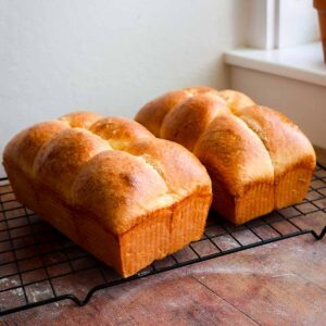 Two loaves of brioche on a wire cooling rack.