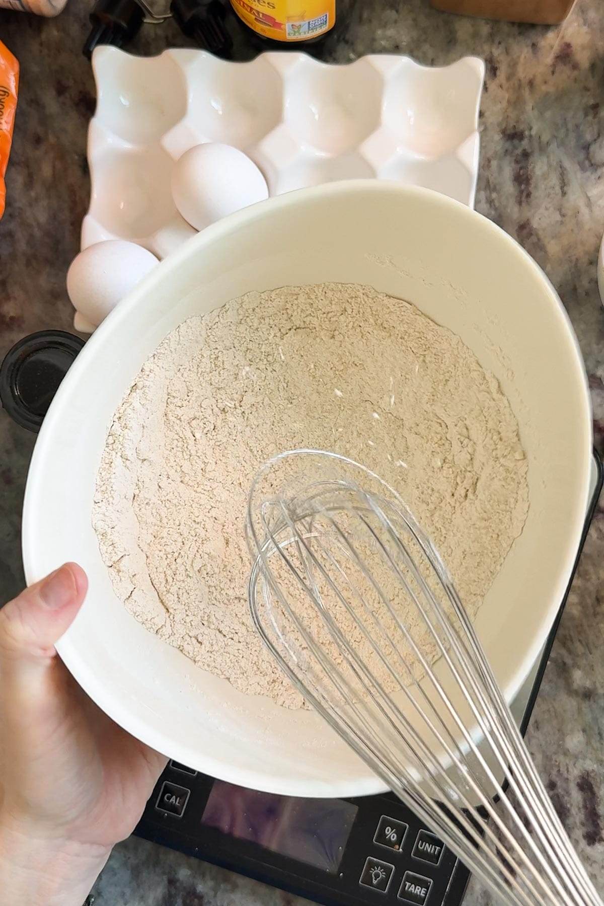 A white bowl with a flour mixture for spiced gingerbread cake loaf.
