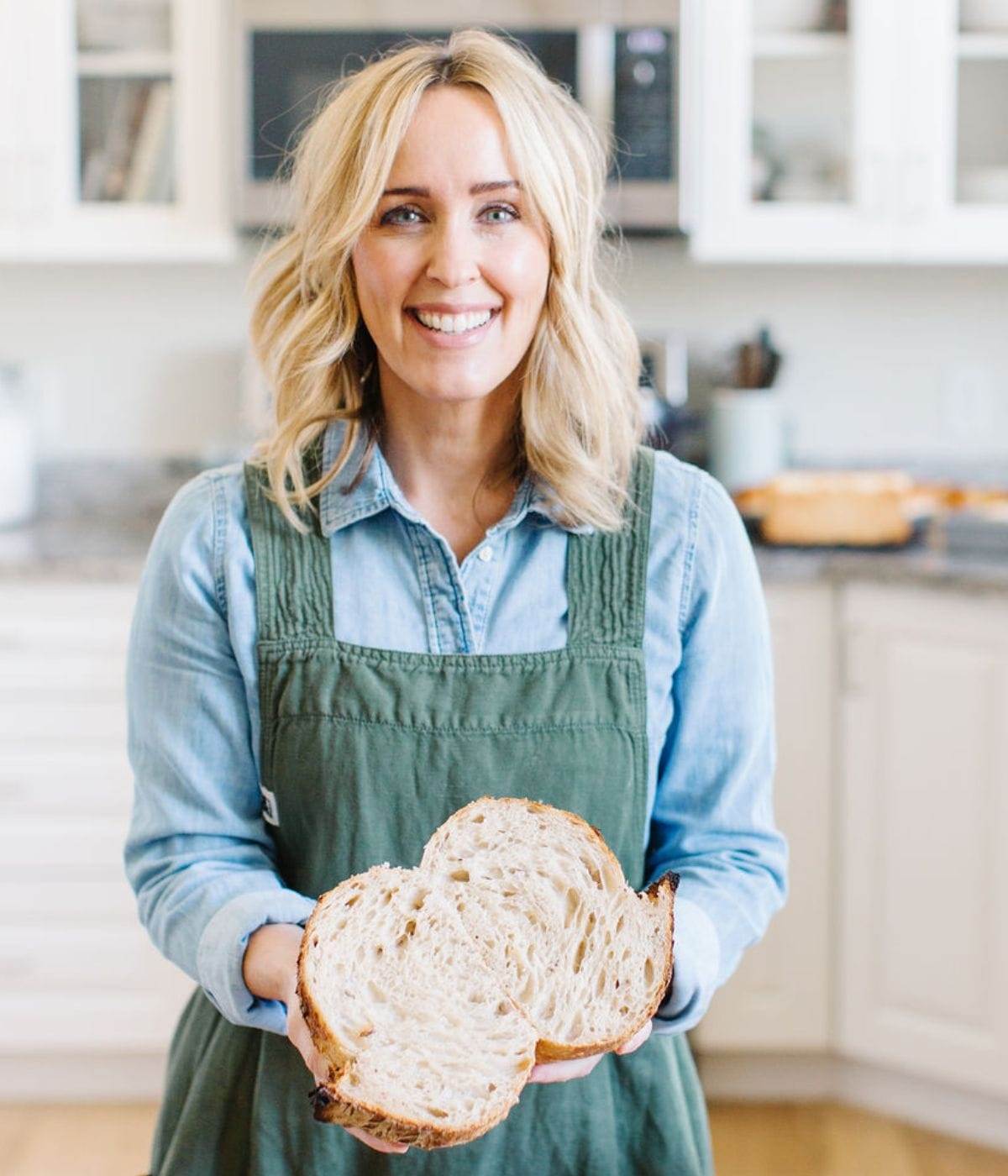 Image of Heather Thomas, That Bread Lady, holding a loaf of sourdough bread in her kitchen.