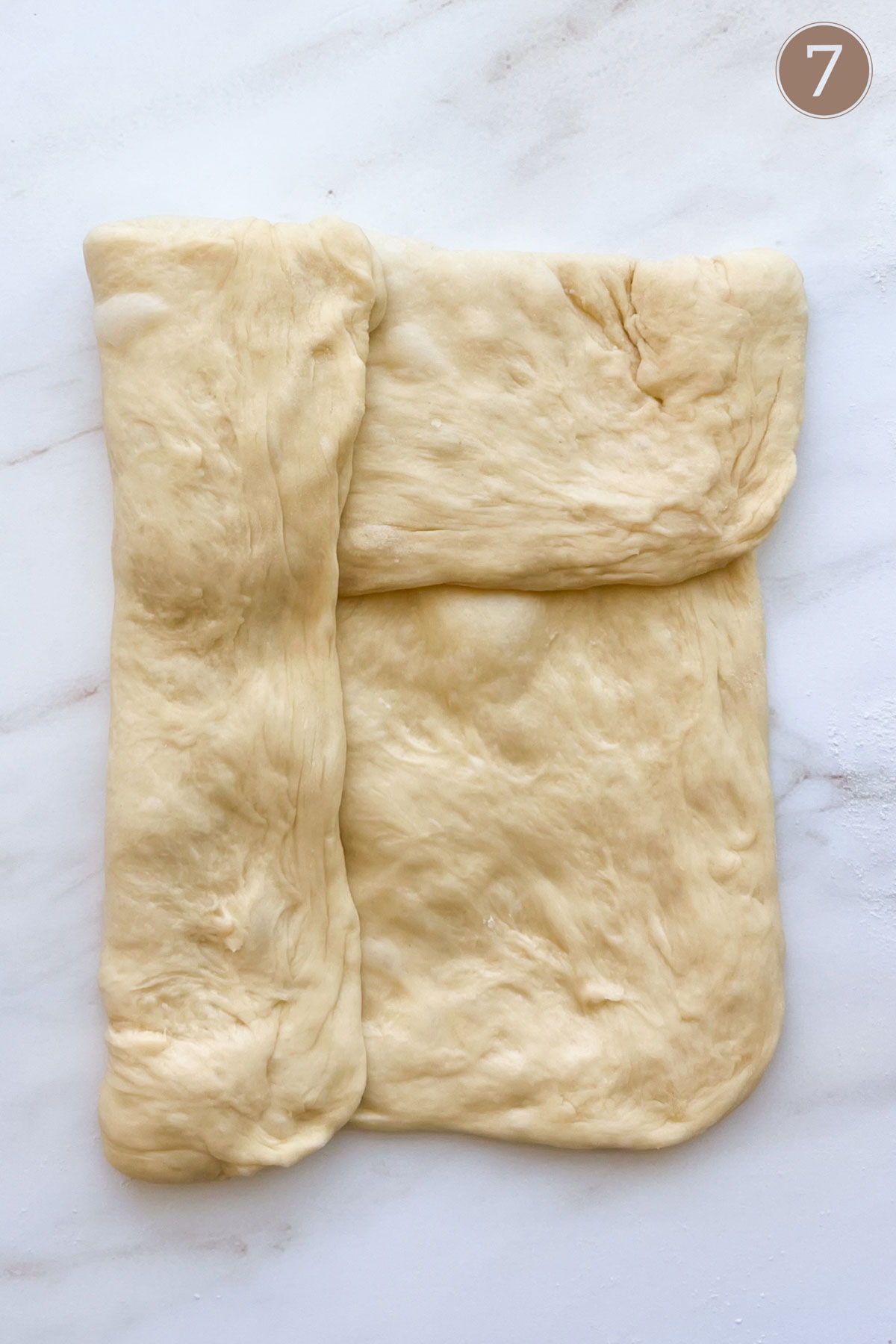 Bread dough folded with the top third folded over, and the left side folded over that.