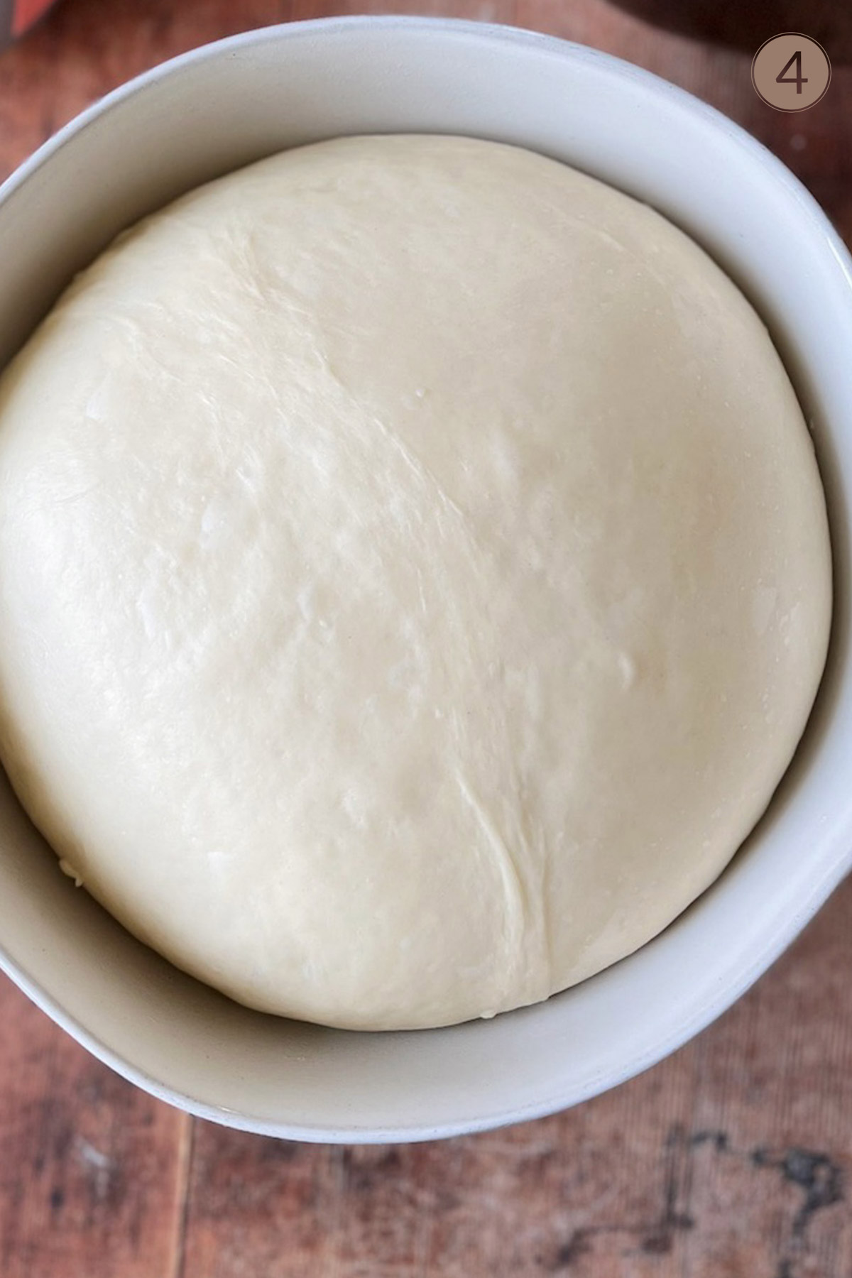 A white bowl with dough risen inside.