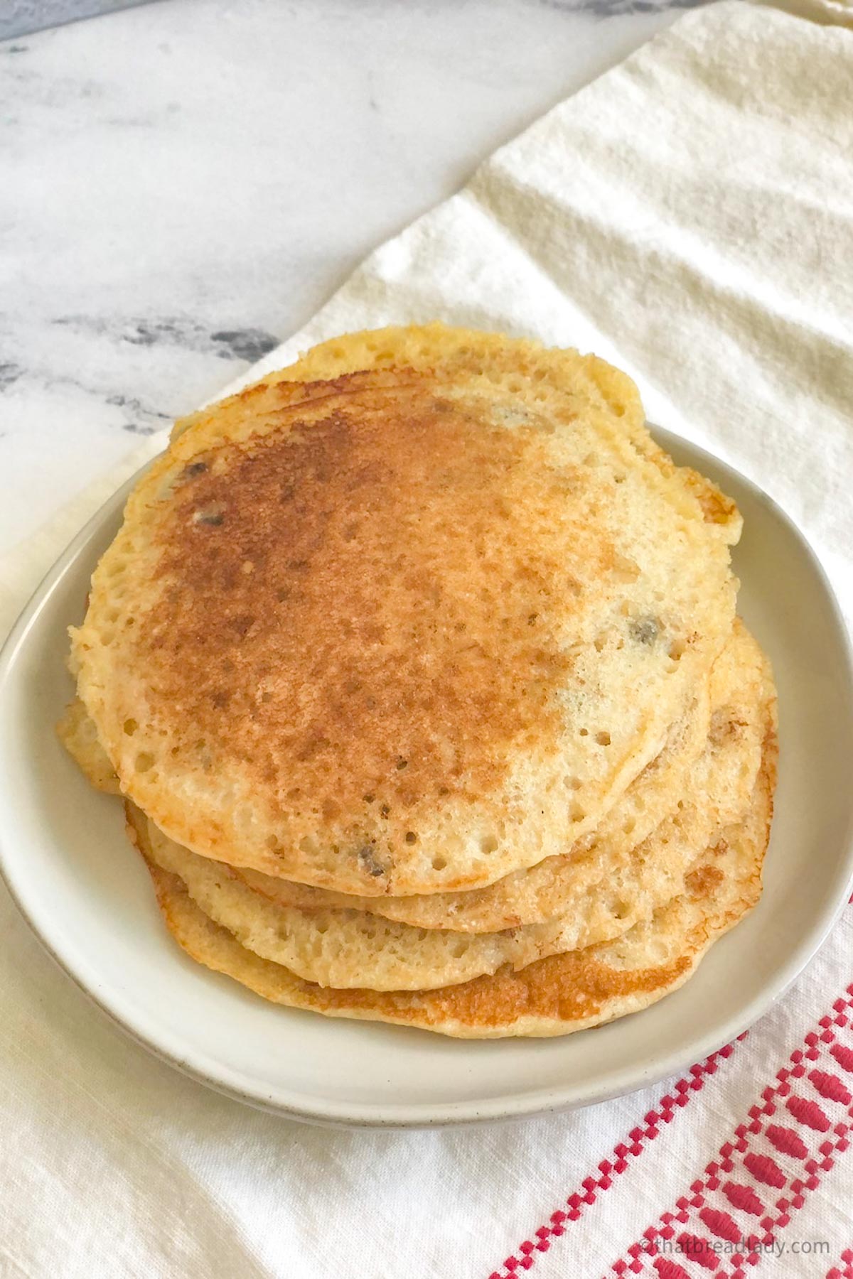A stack of whole wheat pancakes on a white plate.