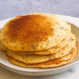 A stack of whole wheat healthy pancakes on a white plate.
