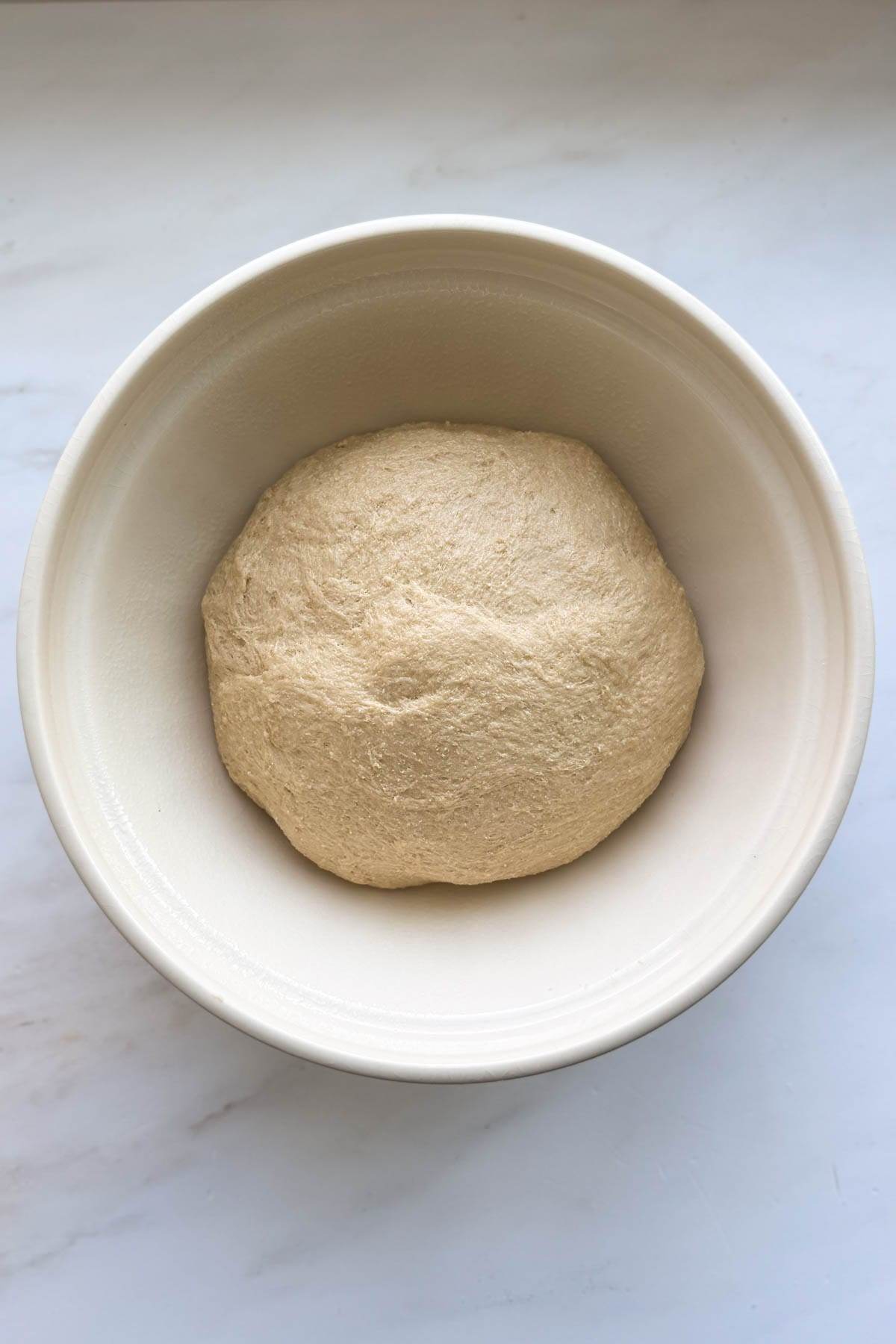 The honey whole wheat bread dough resting in a bowl.